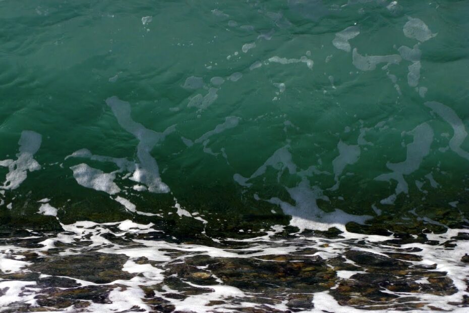 wave green over shingle with froth