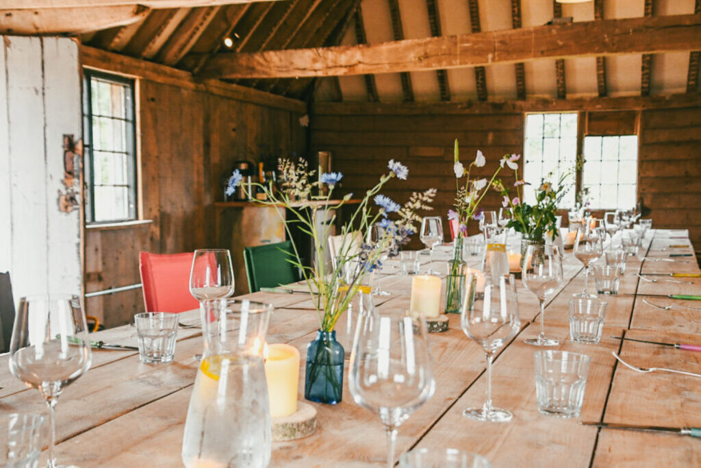 table in barn laid with glasses and flowers, knepp