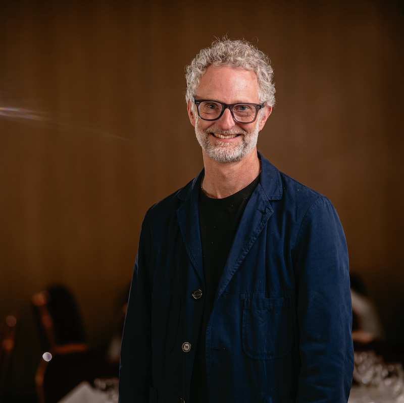 man in glasses curly hair smiling in room with sunlight