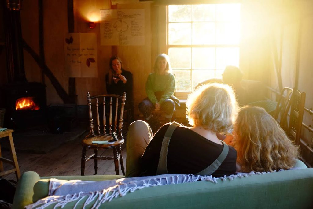 women by fire with sun coming through window cosy