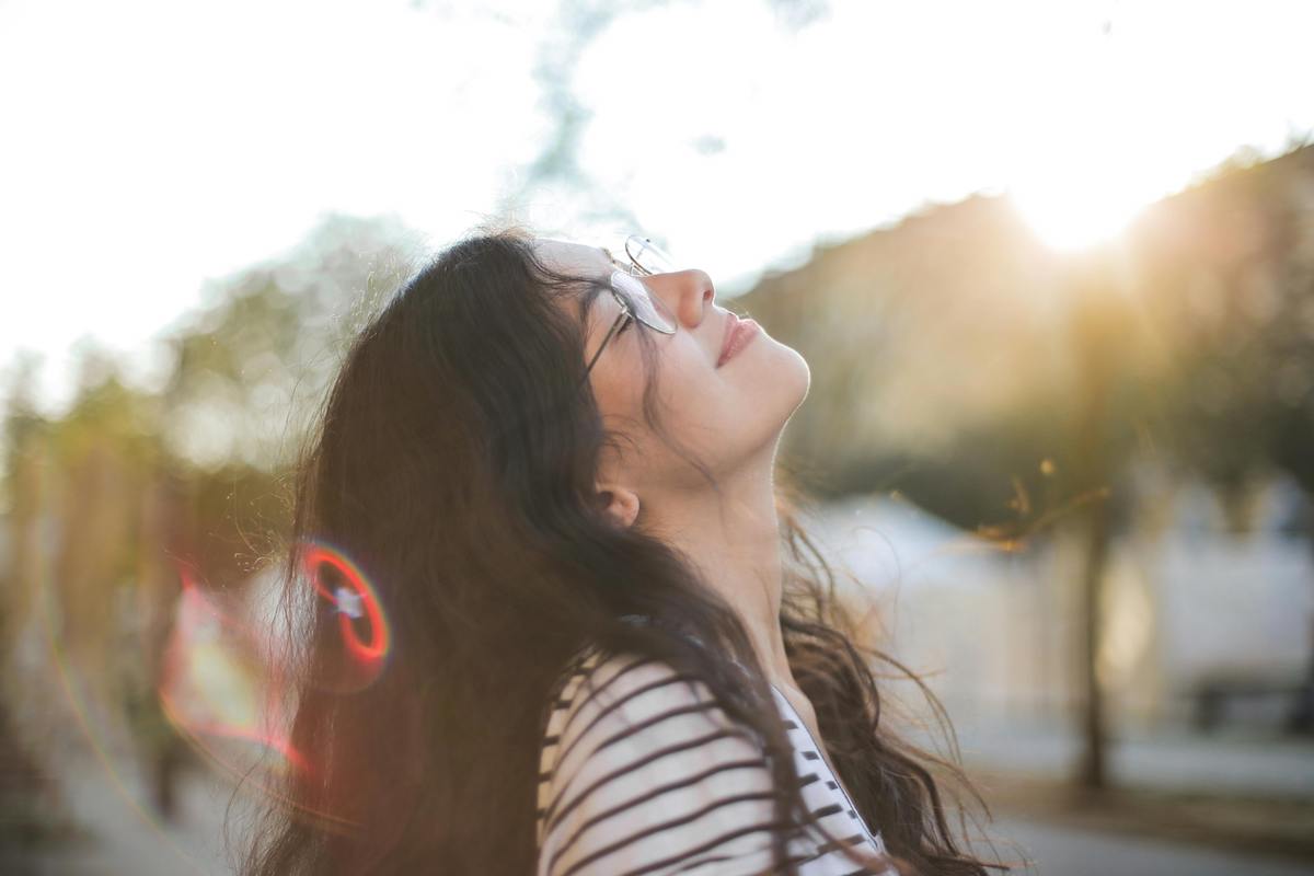 woman smiling looking up at sun