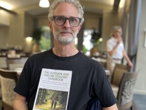 man grey hair glasses holding book
