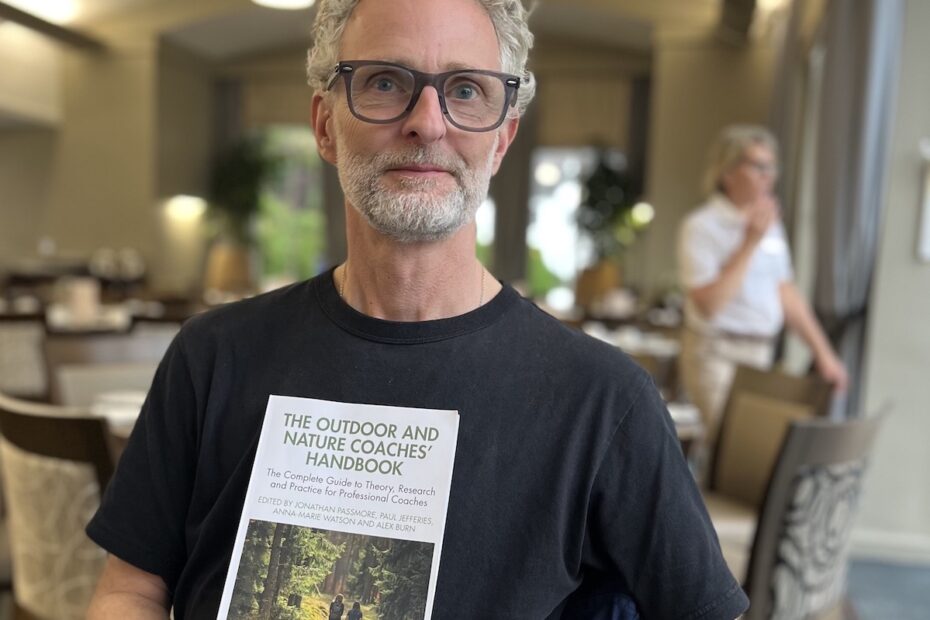 man grey hair glasses holding book